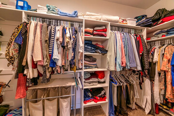 Man and woman clothes in a shared walk in closet with shelves and hanging rods