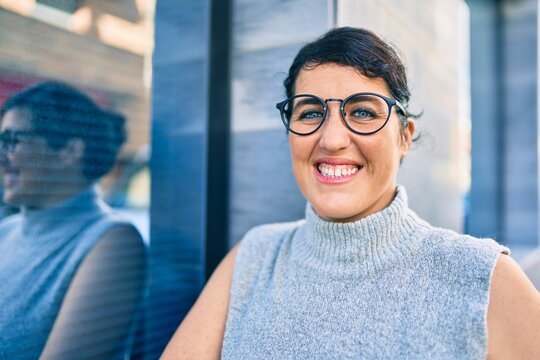 Young plus size woman smiling happy leaning on the wall at the city.