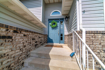 Concrete stairs at home entrance with blue door sidelight and transom window