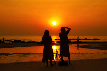 Obraz premium Hua Hin, Thailand - October 24, 2020: Man and Women silhouette standing while shootingon a beach in Hua Hin, Thailand.