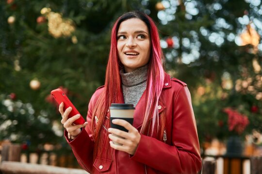 Young caucasian girl smiling happy using smartphone and drinking coffee at the city.