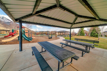 Pavilion with picnic tables and view of kids playground mountain and cloudy sky