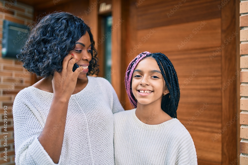 Poster african american mother and daugther hugging and talking on the smartphone at the city.