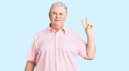 Senior grey-haired man wearing casual clothes smiling with happy face winking at the camera doing victory sign. number two.