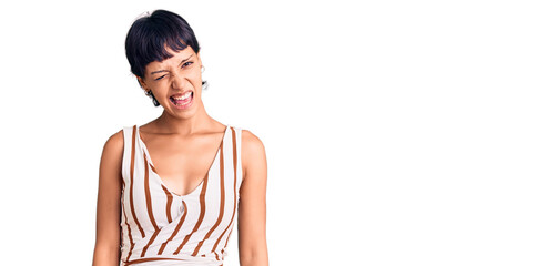 Young brunette woman with short hair wearing summer outfit winking looking at the camera with sexy...