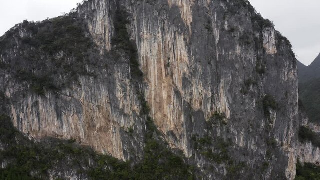 Dramatic karst mountain rock face, rugged texture, rising aerial view
