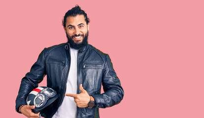 Young arab man holding motorcycle helmet smiling happy pointing with hand and finger