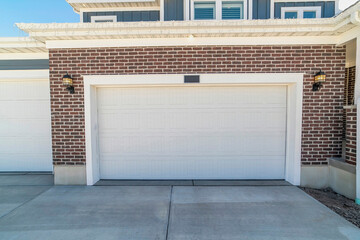 Attached garage of home with wide white door against red brick exterior wall