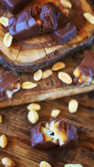 Chocolate candy with peanuts and caramel on a wooden surface.