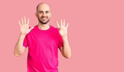 Young handsome man wearing casual t shirt showing and pointing up with fingers number nine while smiling confident and happy.