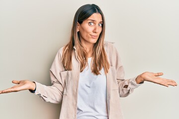Brunette young woman wearing casual clothes clueless and confused expression with arms and hands...