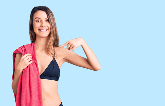 Young beautiful girl wearing bikini and beach towel pointing finger to one self smiling happy and proud