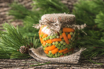 Preserved autumn vegetables. Green Peas and Baby Carrots preserved in a glass jar. Rustic style