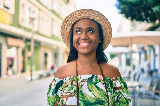 Young african american tourist woman on vacation smiling happy using vintage camera at the city.