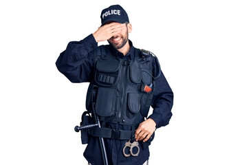 Young handsome man with beard wearing police uniform smiling and laughing with hand on face...