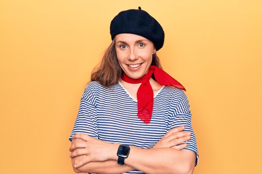 Young beautiful blonde woman wearing french fashion style with scarf and beret happy face smiling with crossed arms looking at the camera. positive person.