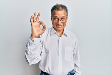 Middle age indian man wearing casual clothes and glasses smiling positive doing ok sign with hand...