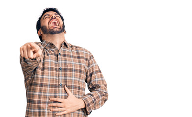 Naklejka premium Young hispanic man wearing casual clothes laughing at you, pointing finger to the camera with hand over body, shame expression
