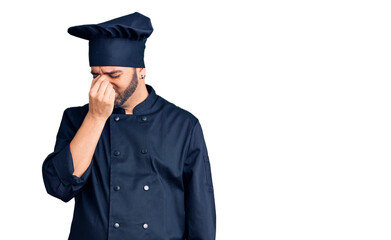 Young hispanic man wearing cooker uniform tired rubbing nose and eyes feeling fatigue and headache. stress and frustration concept.