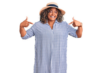 Young african american plus size woman wearing summer hat looking confident with smile on face,...