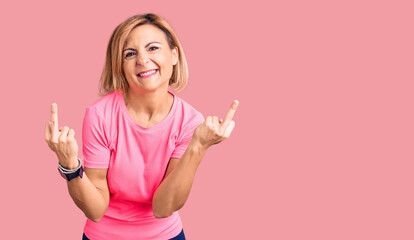 Young blonde woman wearing sportswear showing middle finger doing fuck you bad expression,...