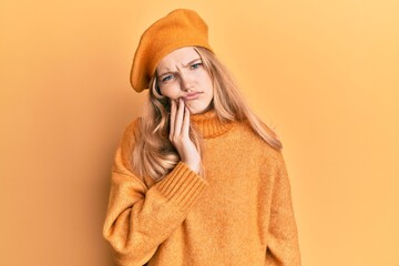 Beautiful young caucasian girl wearing french look with beret touching mouth with hand with painful expression because of toothache or dental illness on teeth. dentist