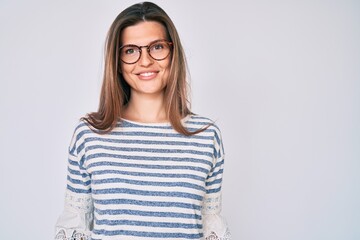 Beautiful caucasian woman wearing casual clothes and glasses looking positive and happy standing...