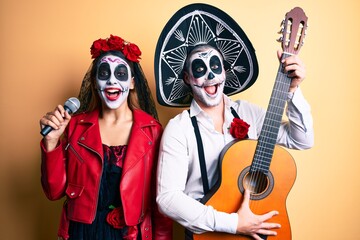 Obraz na płótnie Canvas Couple wearing day of the dead costume playing classical guitar using microphone celebrating crazy and amazed for success with open eyes screaming excited.