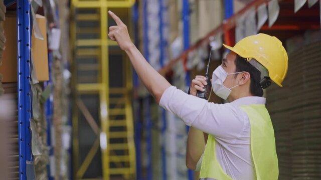 Asian male supervisor working in warehouse with new normal lifestyle.