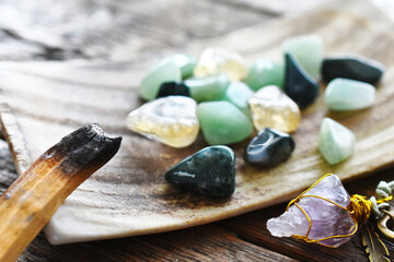 A close up image of a burning smudge stick next to a plate of healing crystals. 