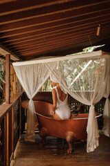 Young woman enjoy spa in outdoor copper bath in jungle. Organic skin care, luxury spa hotel