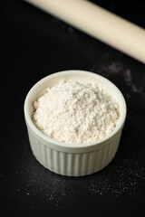 Bowl of flour on dark backdrop.