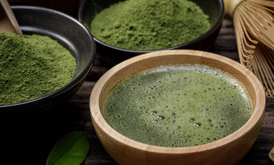 Japanese organic matcha green tea powder in bowl with wire whisk and green tea leaf on wooden background, Organic product from the nature for healthy with traditional style