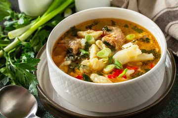 Hot delicious beef soup close-up. Homemade soup with meat, vegetables and gnocchi on a dark stone background.