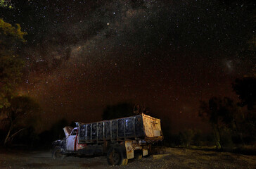 Old truck sits under night sky of stars.