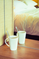 White cup reflect with the mirror with bedroom as background