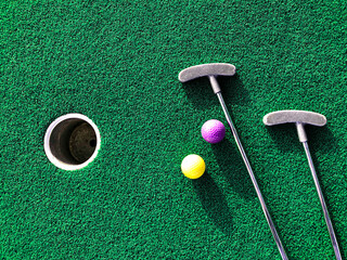 Mini golf clubs and balls on putting green artificial grass carpet