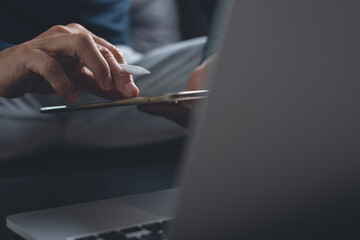 Man hand with stylus pen using digital tablet and working on laptop computer at home office