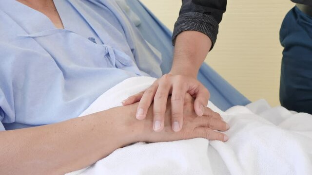 Closeup shot slow motion of man holding a patients hand elderly man in comfort in a hospital ward. Holding Hands, Encouragement and Patient support