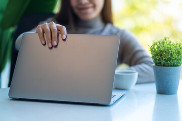 A young asian woman opening a laptop computer, getting ready for work in office
