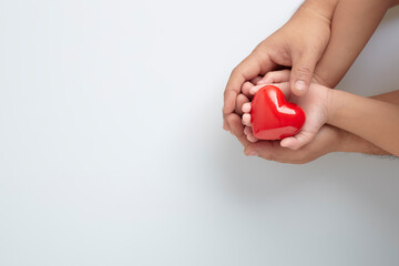 Hands of man and child with a red heart