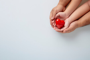 Hands of man and child with a red heart