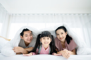 Obraz premium Happy asian family people leisure in bedroom together. Father and mother with daughter relaxing on bed and enjoy funny