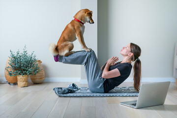 Doga or Doga yoga is the practice of yoga as exercise with dogs. Online yoga at home. Young woman and her dog training together