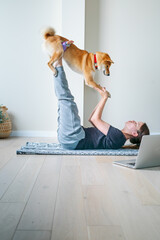 Doga or Doga yoga is the practice of yoga as exercise with dogs. Online yoga at home. Young woman...