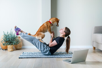 Doga or Doga yoga is the practice of yoga as exercise with dogs. Online yoga at home. Young woman and her dog training together