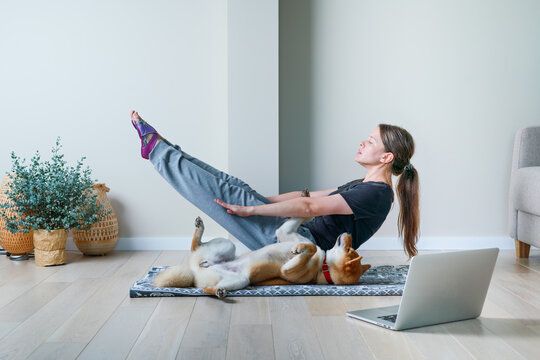 Doga or Doga yoga is the practice of yoga as exercise with dogs. Online yoga at home. Young woman and her dog training together