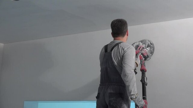 Construction worker puts a finishing touch on wall. Man with polishing machine