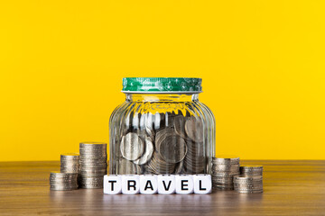 A lot coins in glass jar with yellow background. Saving for Travel concept