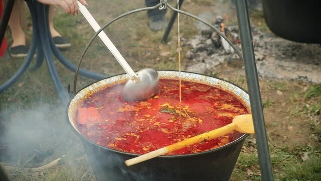 Stir soup Bograch. Soup with paprika, meat, bean, vegetable, dumpling. Traditional Hungarian Goulash in cauldron. Meal cooked outdoors on an open fire. HD